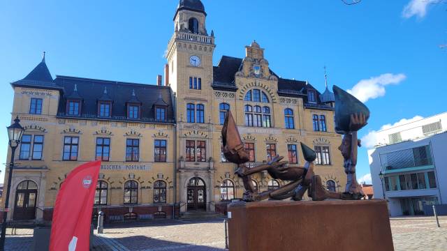 Fotopunkt Historisches Rathaus in Bad Lausick mit moderner Skulptur und roter Info-Fahne – einladender Fotopoint am sonnigen Marktplatz.